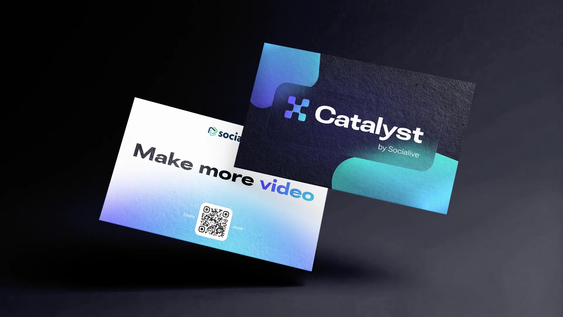 Two business cards floating on black: a dark card with the Spark and the Catalyst wordmark between gradient corners, and a white card reading Make more video with a QR code.